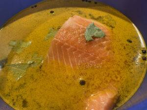 Ein Stück Lachs liegt in einer gelben Marinade.